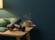 Massagepistole für den Nacken neben Nackenkissen, Wärmekissen und einer Tasse Tee auf einem Beistelltisch
