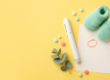 Abnehmspritze und Schwangerschaft: Pen-Injektor neben Babysöckchen und Kalender auf gelbem Hintergrund